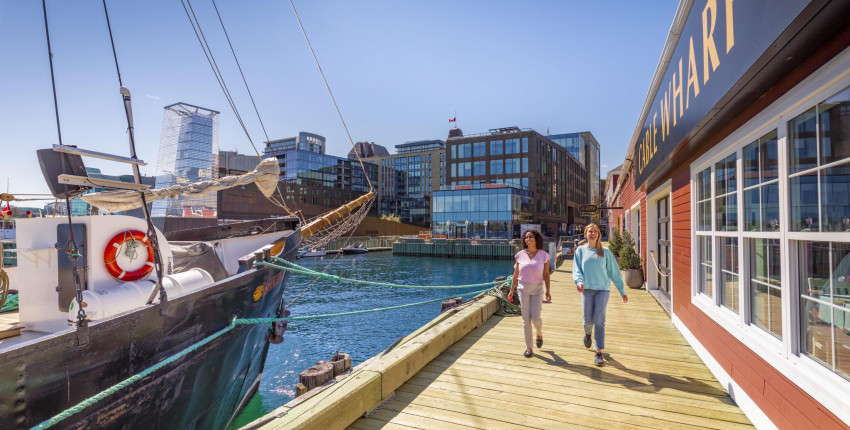 Two people walking on the Halifax boardwalk on a sunny day